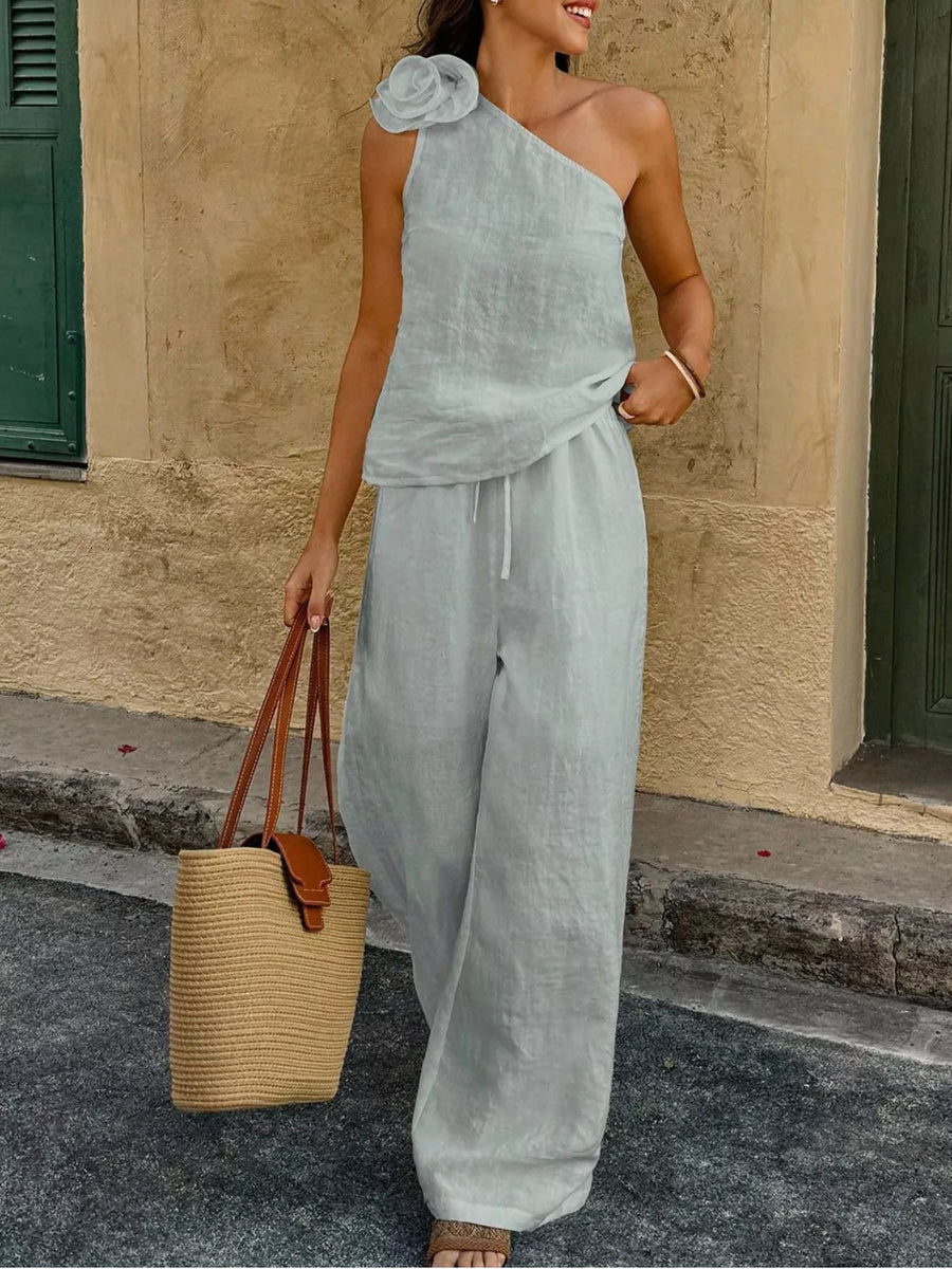Mint green cotton one-shoulder top with floral embellishment and wide-leg pants.