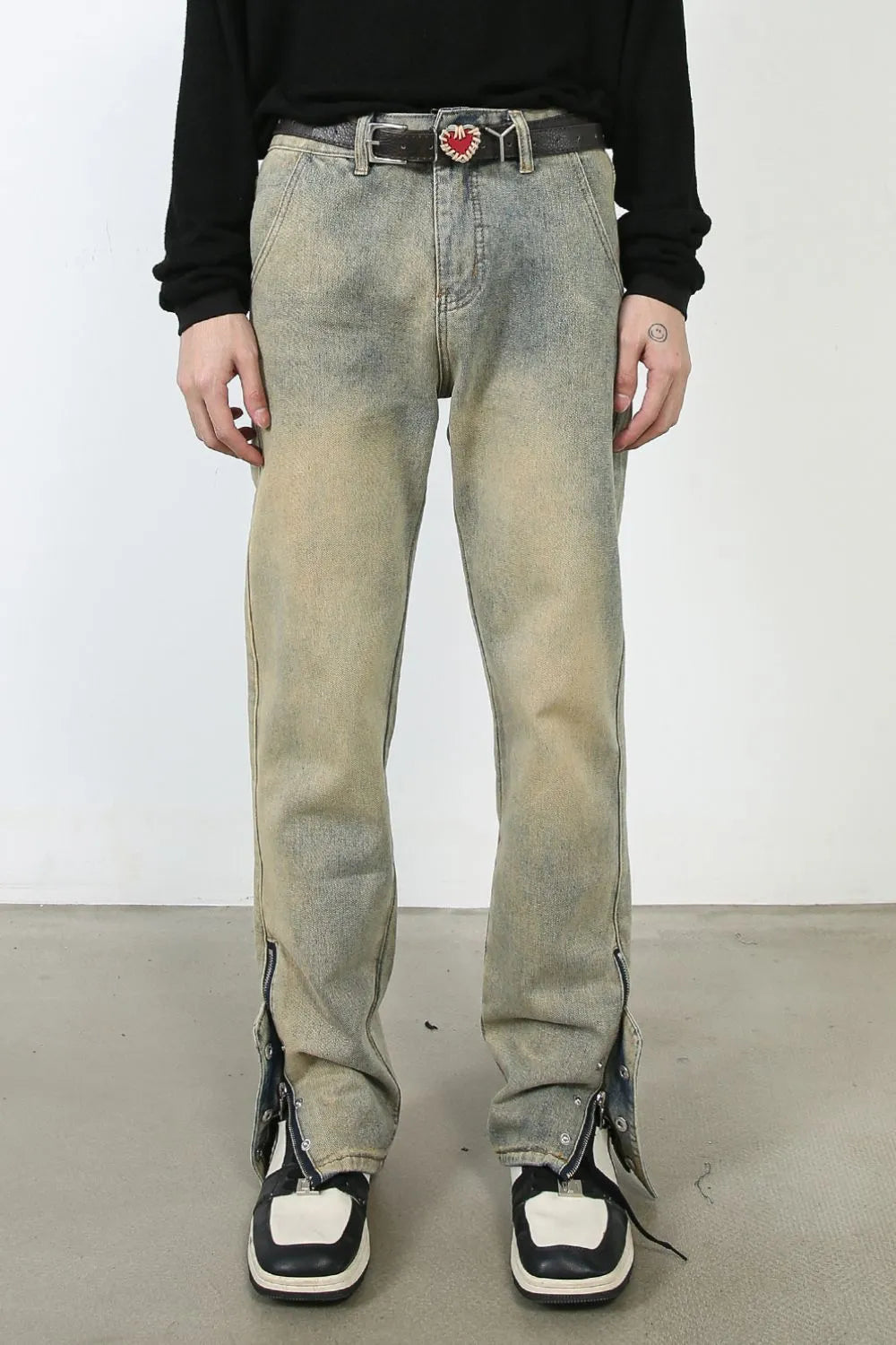 Distressed denim jeans in light wash with split hems and zippers.