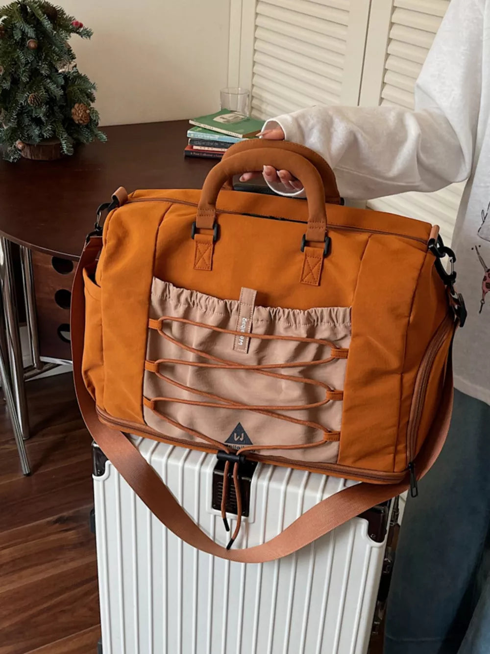 Orange nylon duffel bag with bungee cord detail and tan accents.