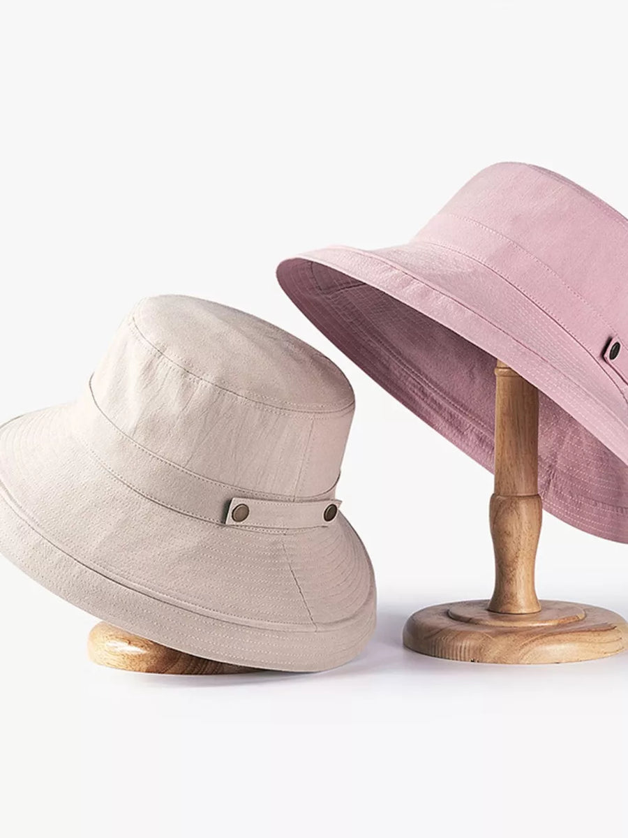 Cotton bucket hats in pink and khaki with brass hardware detail