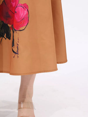 Brown midi dress with a large pink and red floral print and a flared skirt.