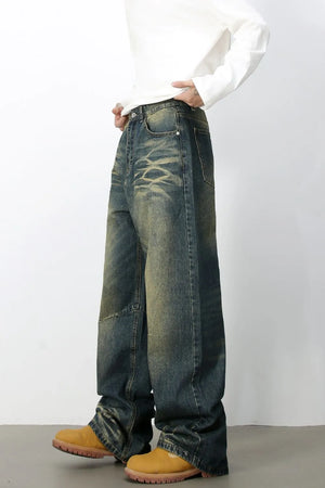 Distressed denim wide-leg trousers in medium wash with a faded, artisanal look.