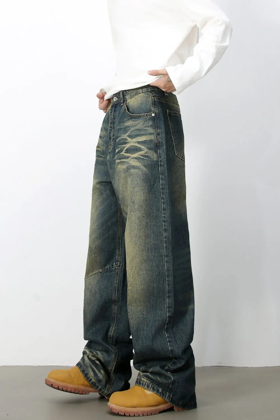 Distressed denim wide-leg trousers in medium wash with a faded, artisanal look.