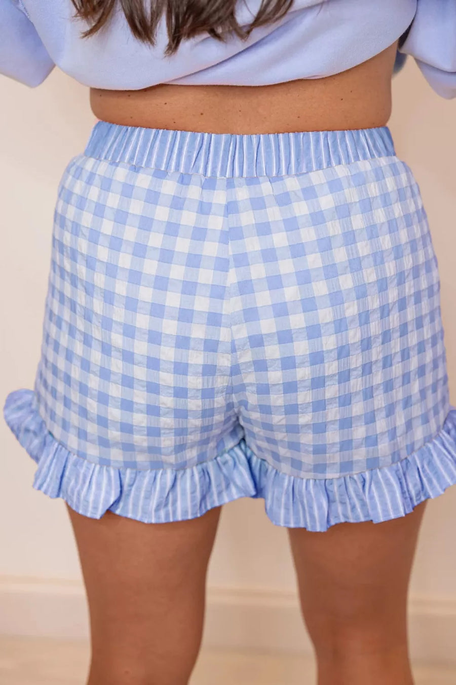 Light blue gingham cotton shorts with ruffled hem and drawstring waist.
