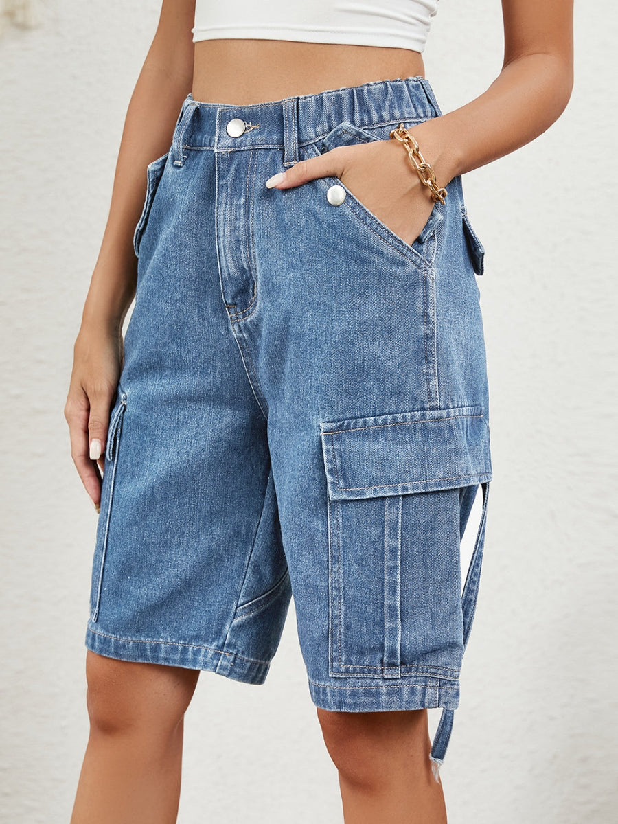 Medium wash denim bermuda shorts with buttoned cargo pockets and utility straps.