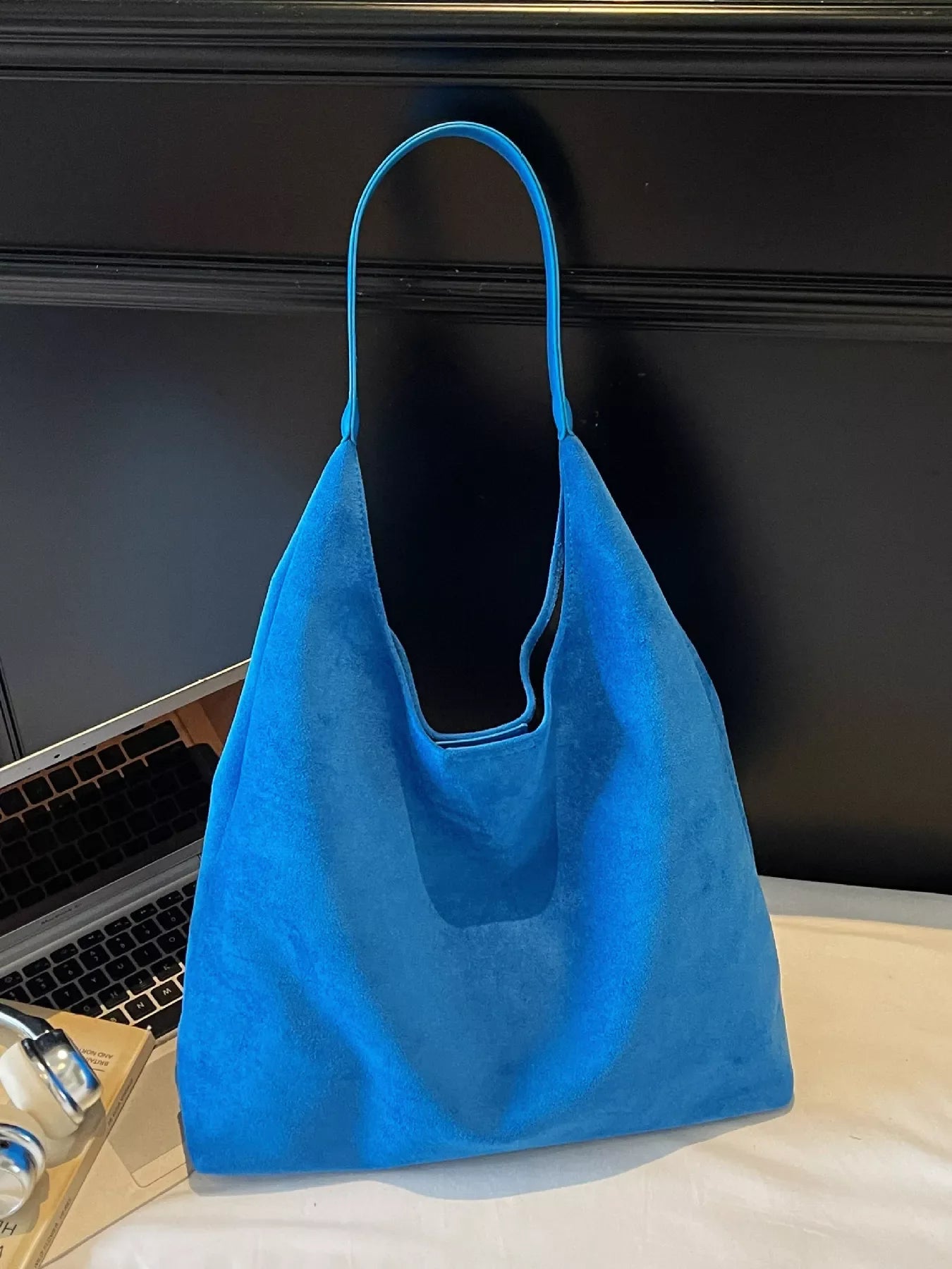 Sky blue suede shoulder bag with a single strap and slouchy silhouette.
