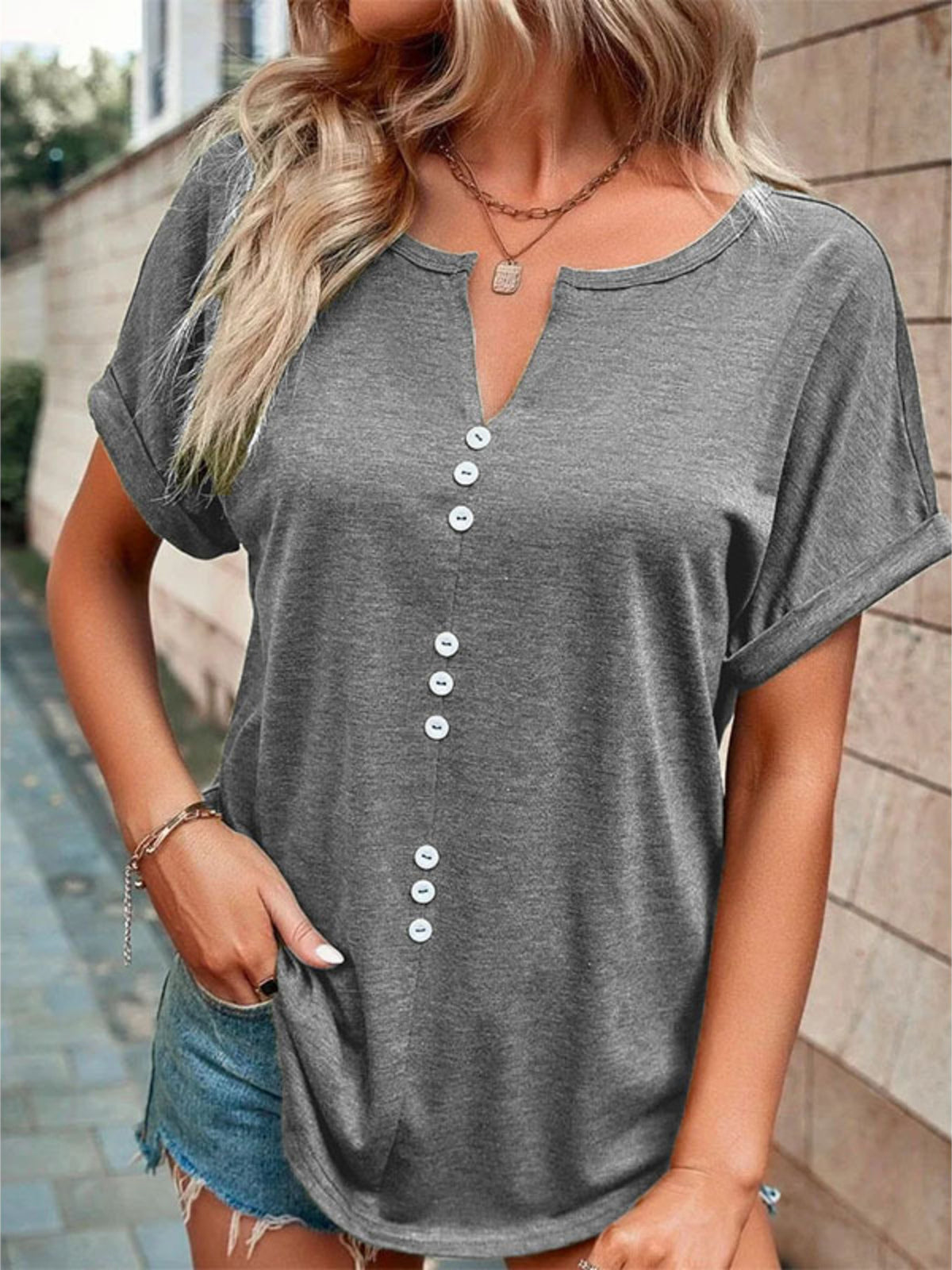 Grey short sleeve t-shirt with V-neck and decorative buttons.