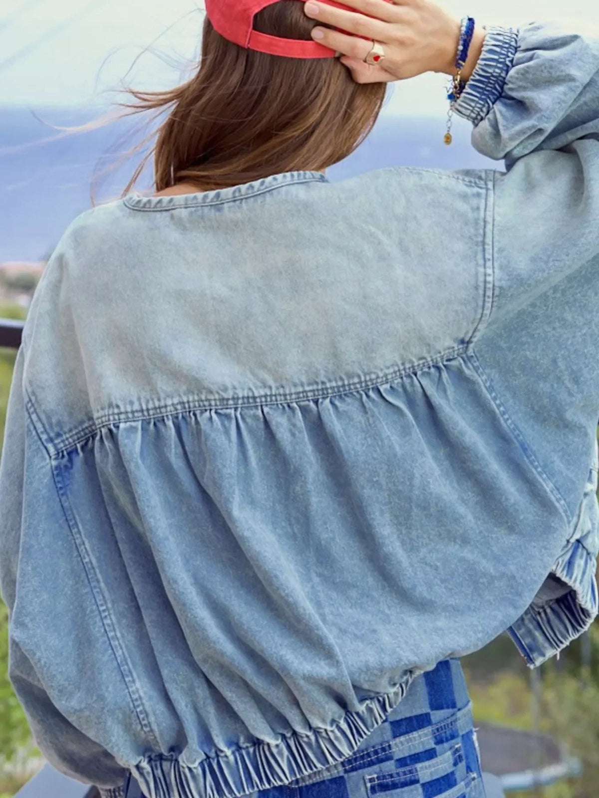 Washed denim jacket with gathered back detail and elastic cuffs.