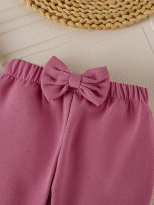 Baby girl's flare pants in Moonlit Mauve with a decorative bow detail on the waistband.