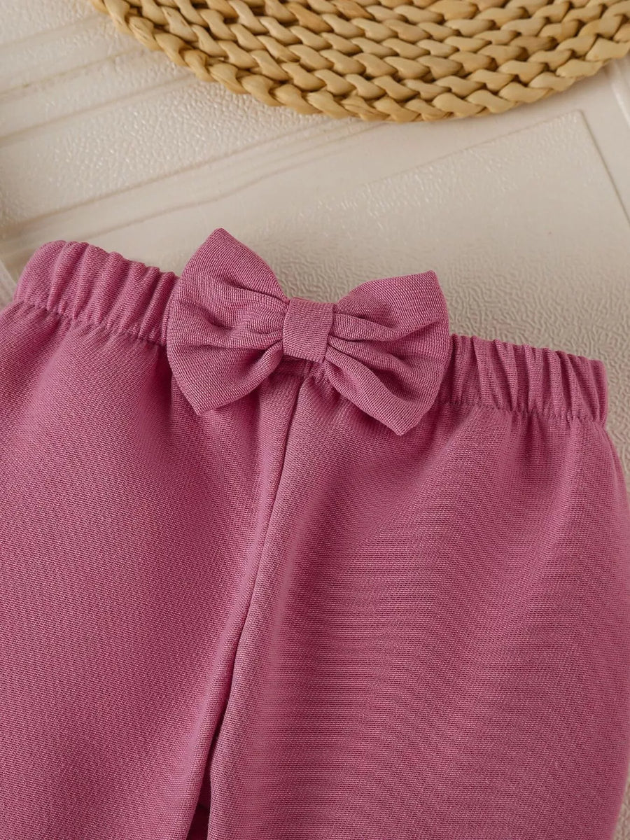 Baby girl's flare pants in Moonlit Mauve with a decorative bow detail on the waistband.