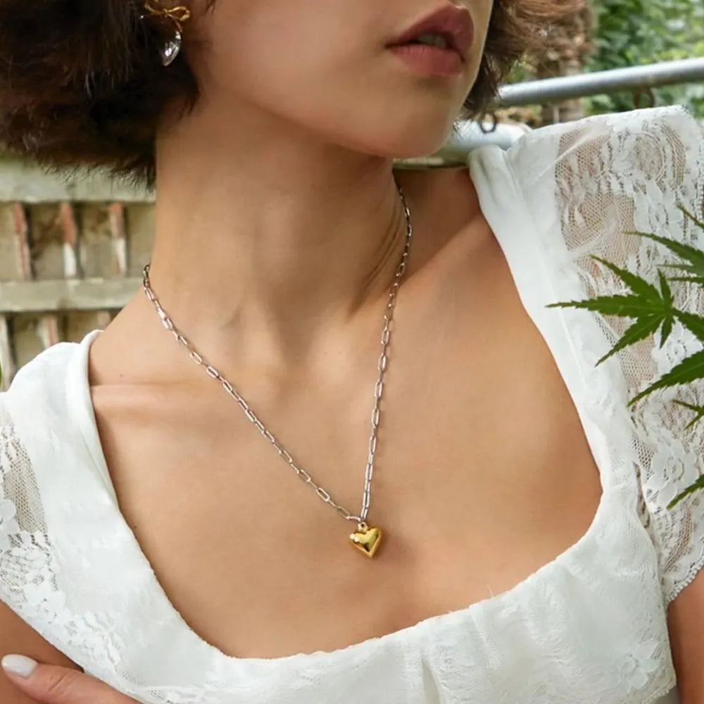 Two-tone heart chain necklace in silver with a gold heart pendant.