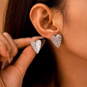 Silver heart leaf stud earrings with textured detail.
