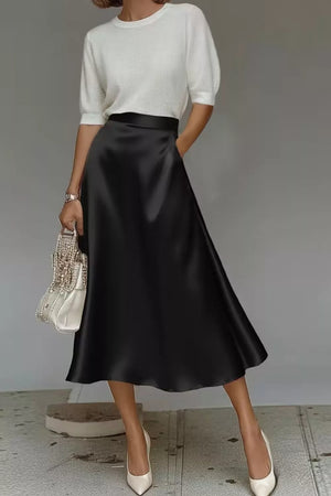 Black a-line midi skirt with hidden pockets, made of lustrous fabric.