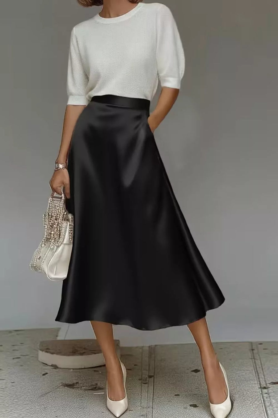 Black a-line midi skirt with hidden pockets, made of lustrous fabric.