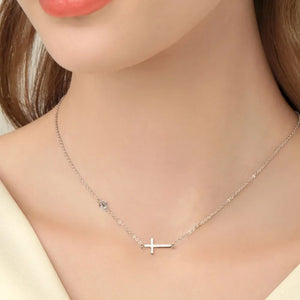 Silver asymmetrical cross pendant necklace with a single stone accent.