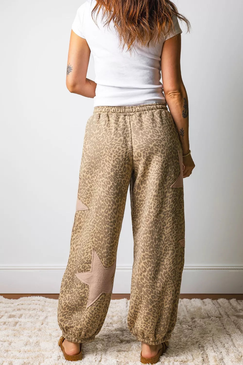 Leopard print relaxed fit pants in brown with star patches and elastic cuffs.