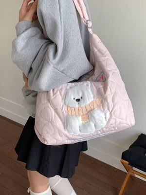 Blush pink quilted crossbody bag with heart pattern and white bear applique wearing a scarf.