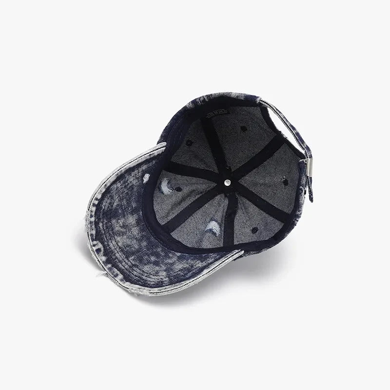 Acid wash distressed denim baseball cap with frayed brim and adjustable strap.
