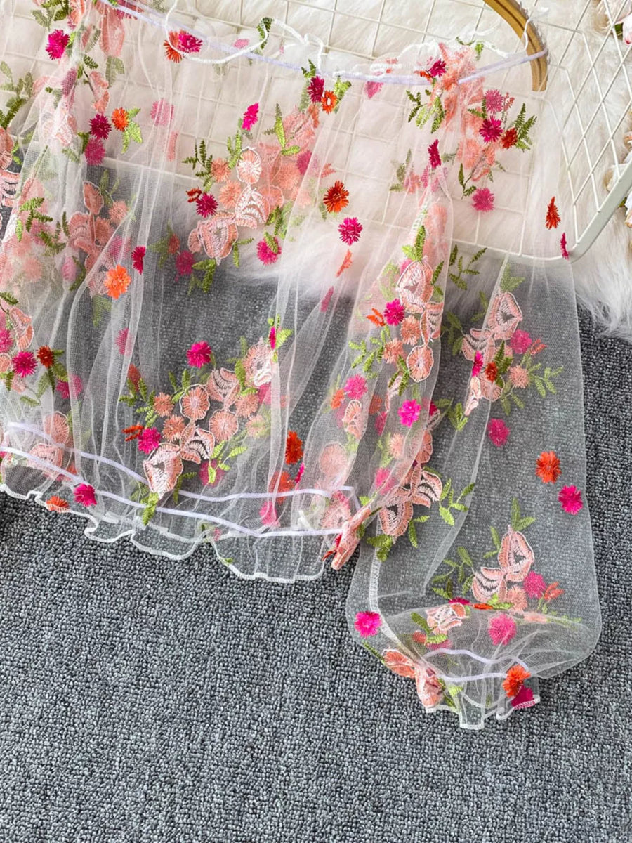White sheer t-shirt with off-shoulder neckline and embroidered floral details.