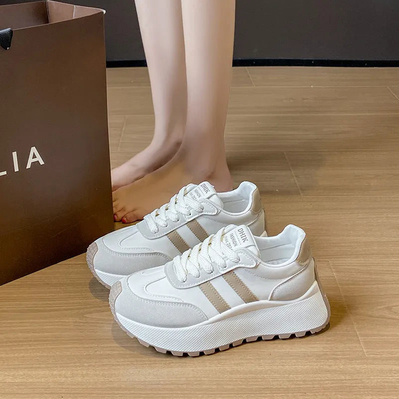 White platform trainers with beige stripe detail and lace-up closure.