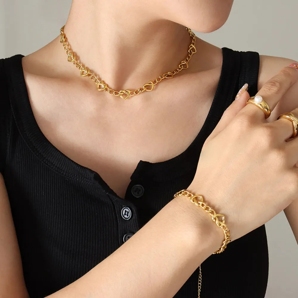 Gold heart link chain necklace and bracelet set with rings on hand
