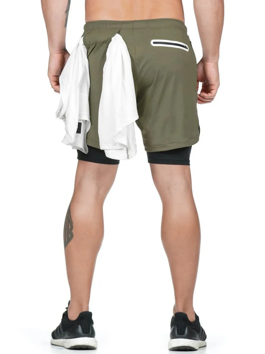 Moss green layered performance shorts with black compression liner and white towels tucked into waist.