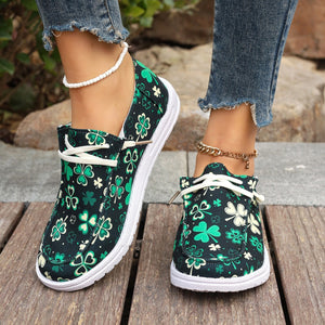 Clover print canvas slip-on sneakers with decorative white laces and white soles.
