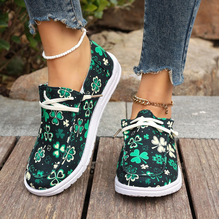 Clover print canvas slip-on sneakers with decorative white laces and white soles.