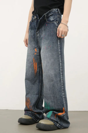 Painterly wide-leg denim jeans in medium wash with abstract paint splatters and wide leg cut.