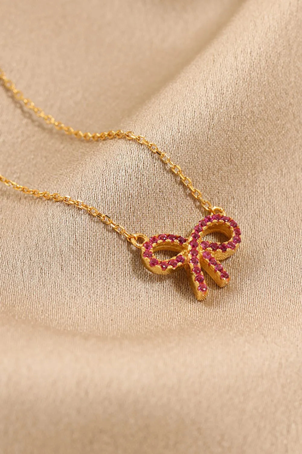 Gold bow pendant necklace with ruby embellishments