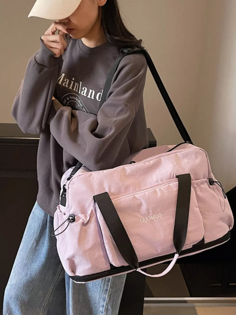 Pink duffle bag with black straps and multiple exterior pockets, GUOMISS logo.