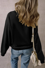 Black crewneck sweatshirt with long sleeves, casual fit, worn with jeans and a cream crossbody bag.