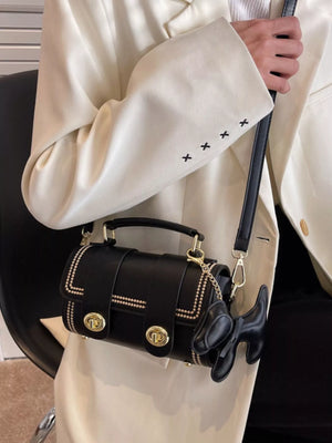 Black PU leather crossbody bag with gold hardware and dog charm accessory.