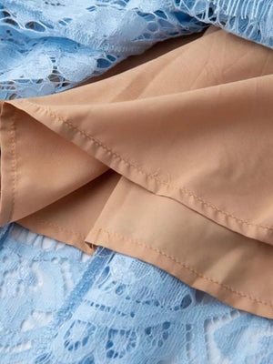 Blue lace dress detail with tan lining and visible stitching.