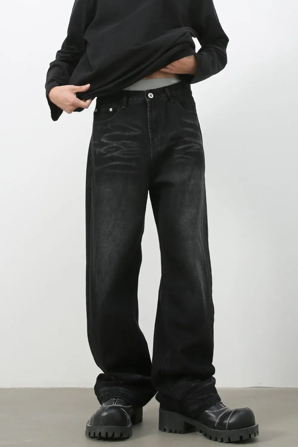Faded black baggy denim trousers with a relaxed fit and visible distressing.