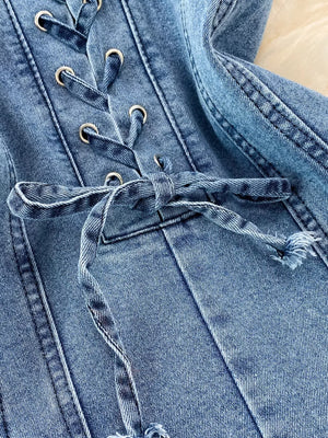 Blue denim corset dress with lace-up detail and silver grommets.