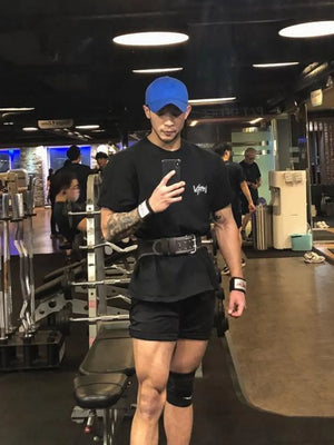 Black oversized graphic tee with short sleeves and crew neck, worn by a man in a gym.