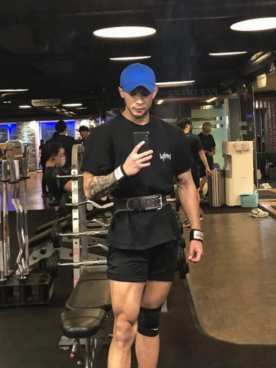 Black oversized graphic tee with short sleeves and crew neck, worn by a man in a gym.