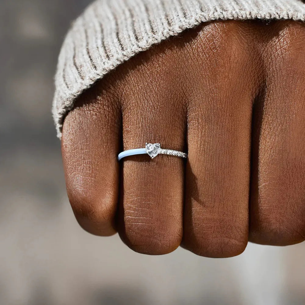 Light blue enamel ring with pave band and heart shape stone on a hand.