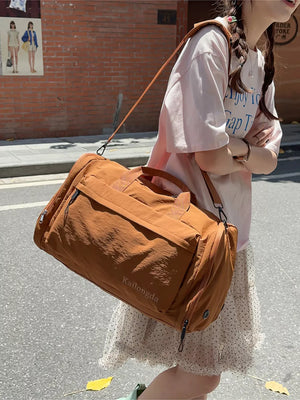 Brown Oxford cloth travel bag with detachable strap and front pocket detail.
