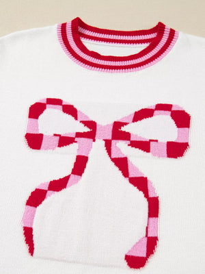 White sweater with red and pink checkered bow graphic and striped neckline.