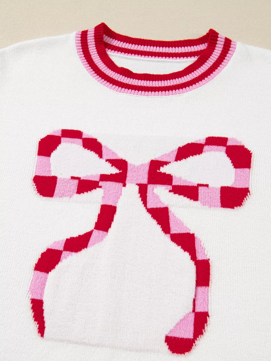 White sweater with red and pink checkered bow graphic and striped neckline.
