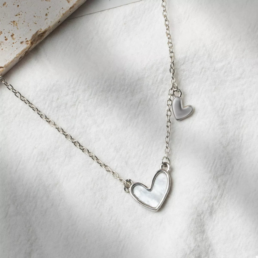 Silver necklace with a white heart pendant and a small dangling heart charm.