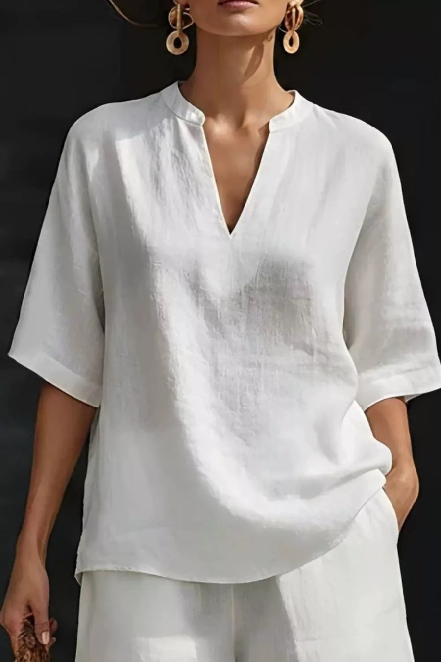 White notched top with V-neck and elbow-length sleeves, paired with pocketed shorts.