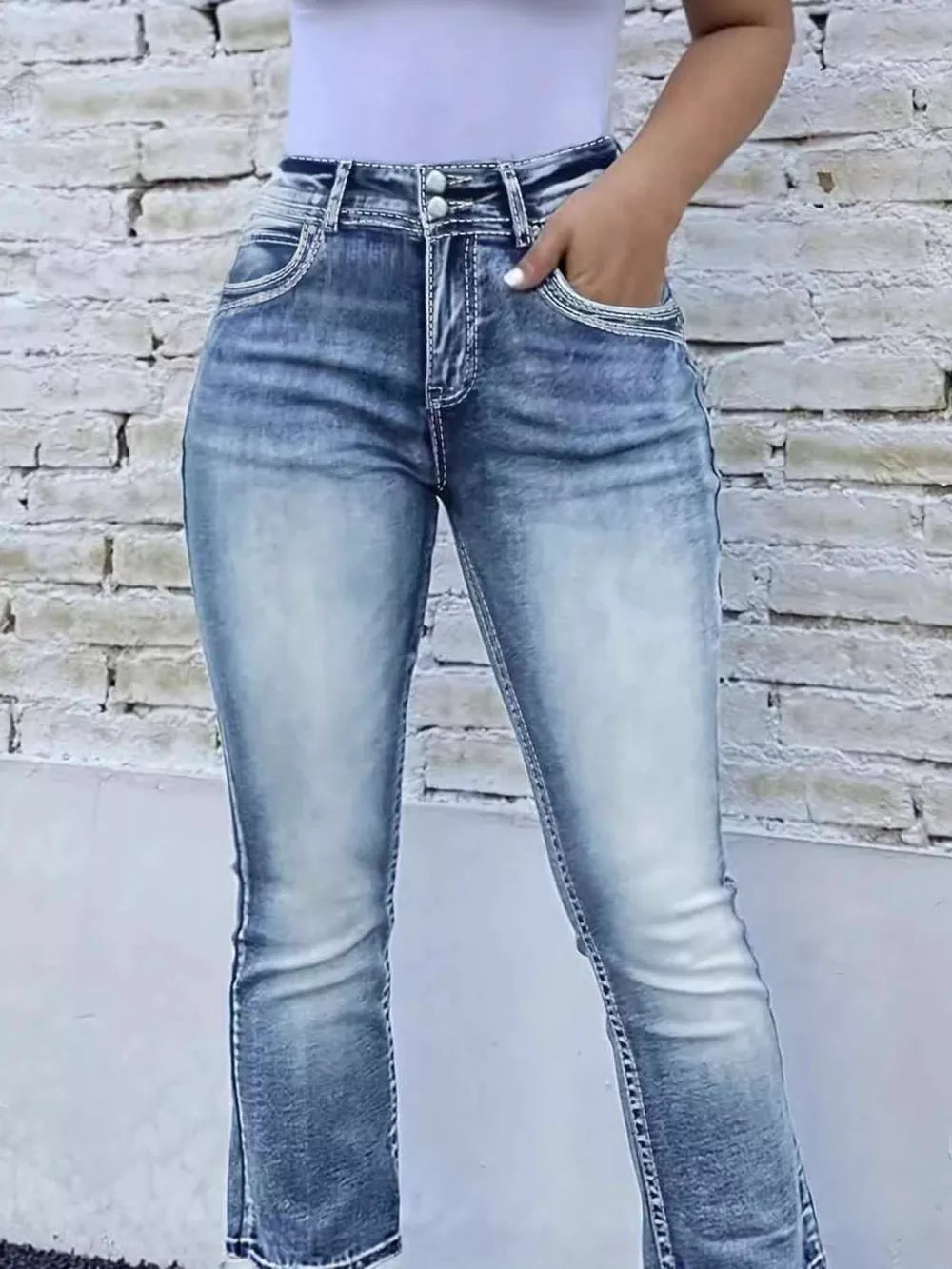 Blue cotton high-waisted bootcut jeans with button closure and contrast stitching.