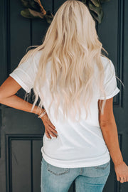 White graphic t-shirt with rolled sleeves and a casual fit, worn by a woman.