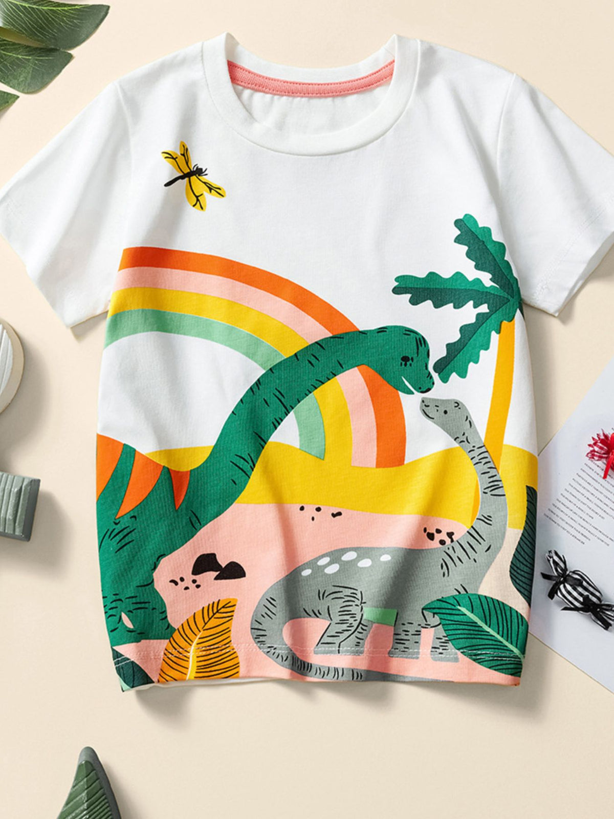 White cotton crew neck toddler t-shirt with dinosaur and rainbow graphic.