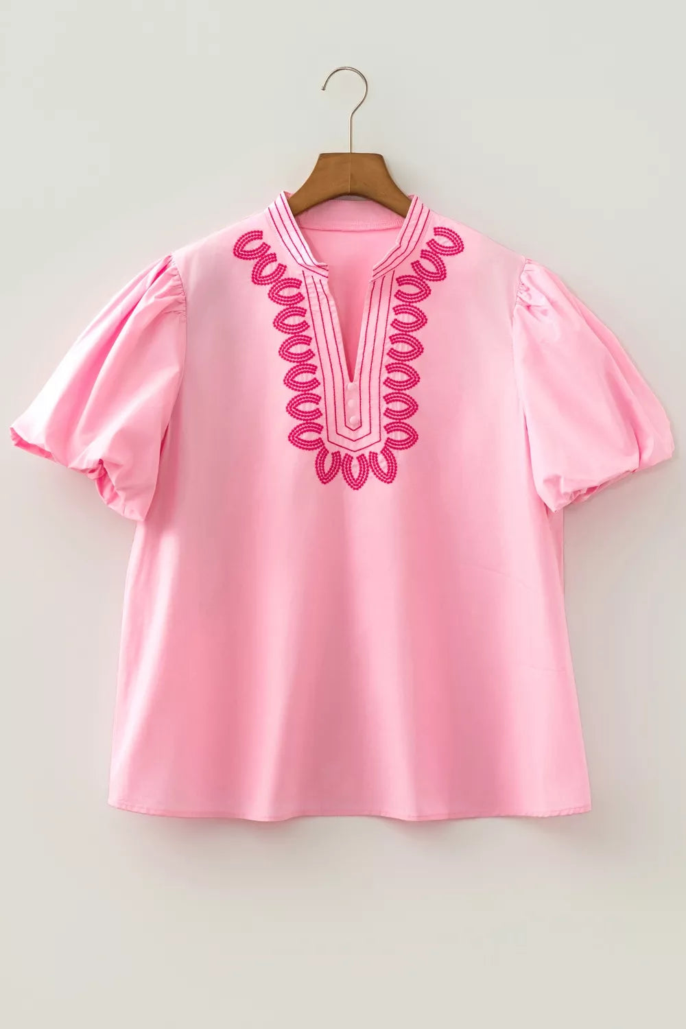 Pink cotton shirt with puff sleeves and contrast embroidery detail at neckline.
