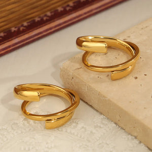 Gold sculptural spiral steel ring with a modern, open design.