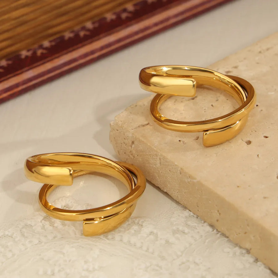 Gold sculptural spiral steel ring with a modern, open design.